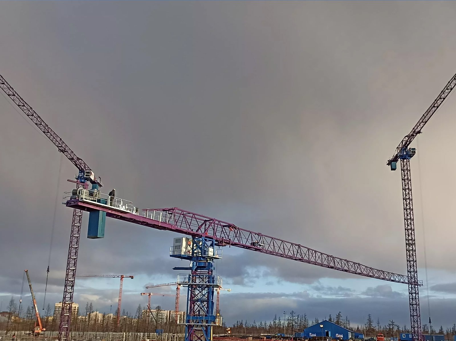 Multiple tower cranes operating under overcast skies at a construction site