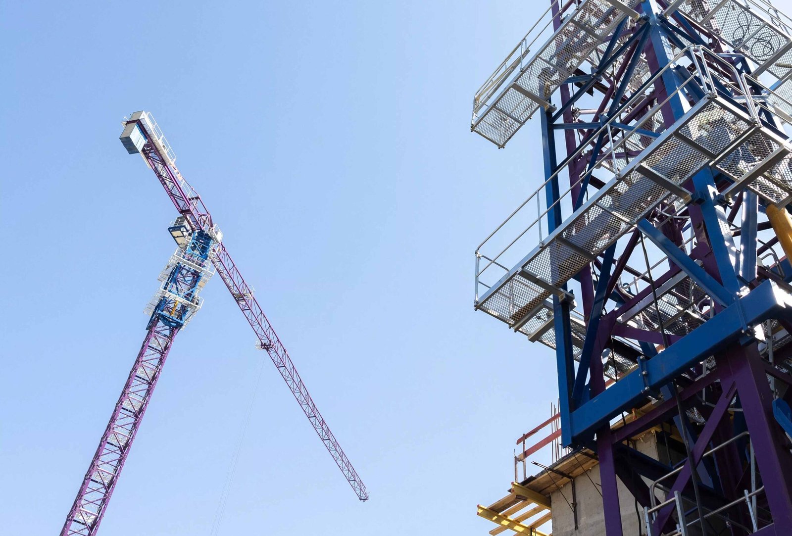 Tower cranes at a construction site under a clear blue sky